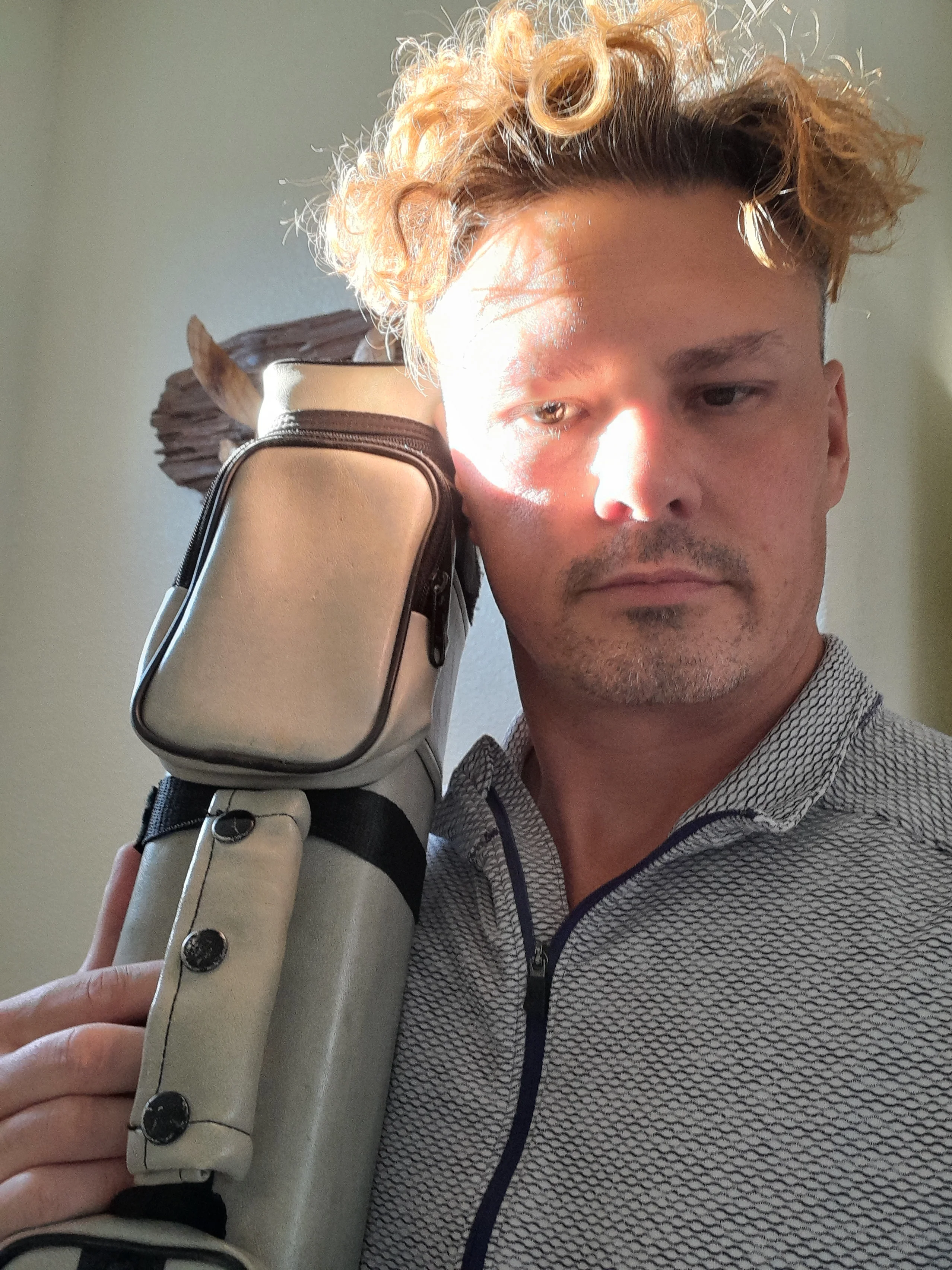 Christopher Lazok holding a custom cue case over his shoulder in an operations suite in Carson City, Nevada.